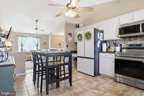 a kitchen with stainless steel appliances a stove a refrigerator a microwave a dining table and chairs with wooden floor