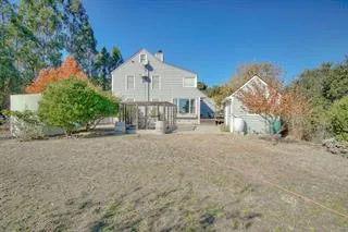 a view of a house with large trees and fence