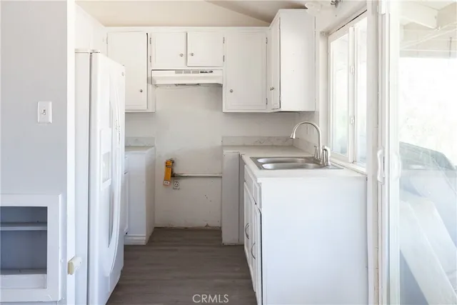 a view of a kitchen with refrigerator and white cabinets