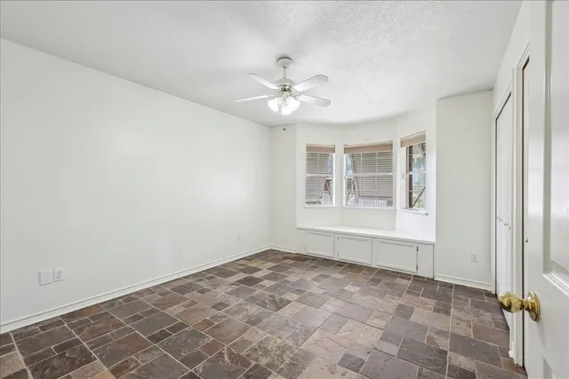 an empty room with windows and fan