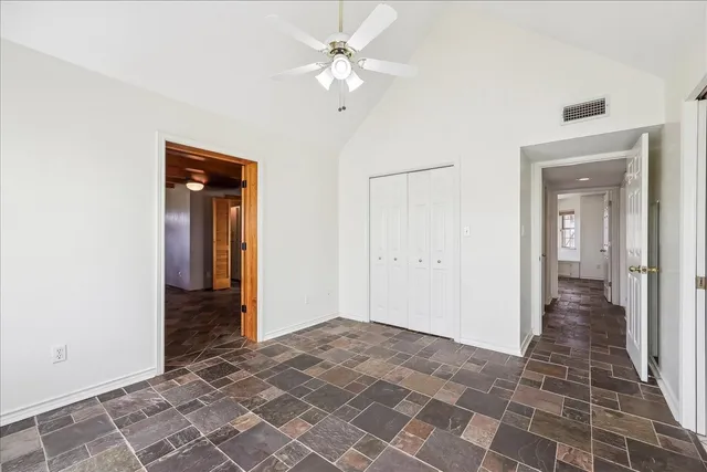an empty room with closet and a chandelier fan