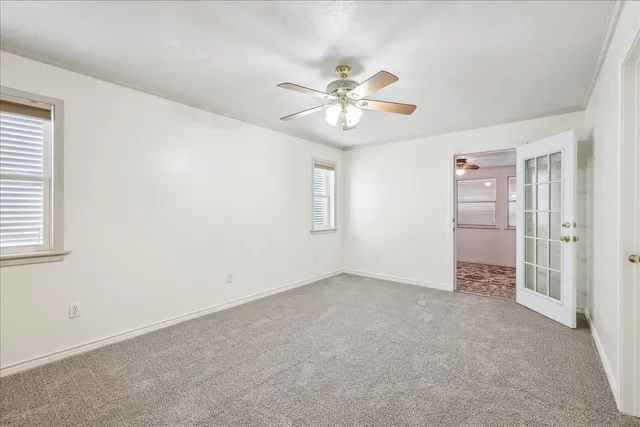 a view of an empty room with chandelier fan