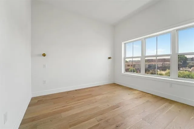 a view of an empty room with a window and wooden floor