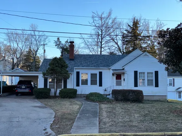 a view of a house with a small yard and large trees