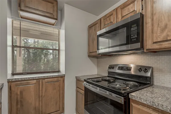 a kitchen with granite countertop cabinets stainless steel appliances and a window