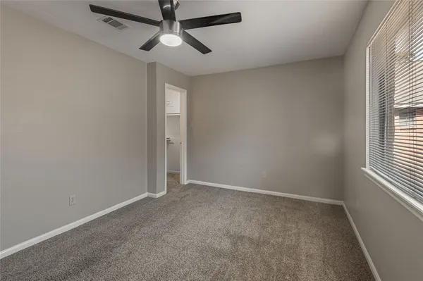 an empty room with windows and fan