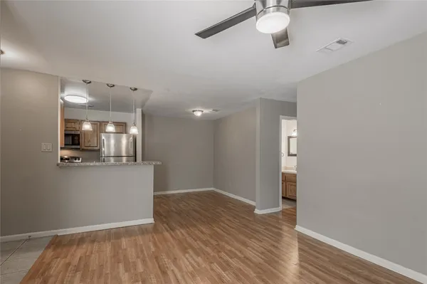 a view of kitchen and empty room with wooden floor