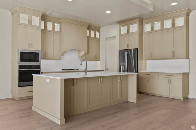 2955 East Rimrunner Drive St. George, UT 84790 - Photo 7 of 35 Spacious kitchen featuring an expansive center island with seating, extensive cabinetry with illuminated glass-front uppers, stainless steel appliances, a built-in microwave and oven, and wood-finish flooring