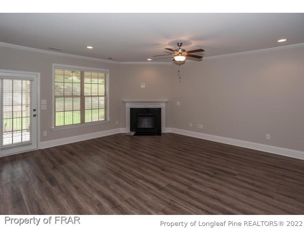 160 Winged Foot Road Pinehurst, NC 28374 - Photo 12 of 35 an empty room with wooden floor chandelier fan and windows
