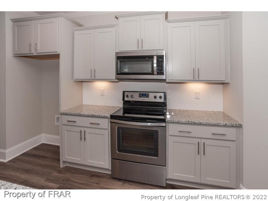 160 Winged Foot Road Pinehurst, NC 28374 - Photo 18 of 35 a kitchen with granite countertop white cabinets and stainless steel appliances