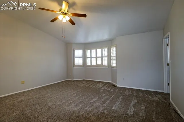 a view of an empty room with a ceiling fan and a window