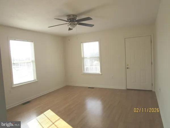 an empty room with wooden floor fan and windows
