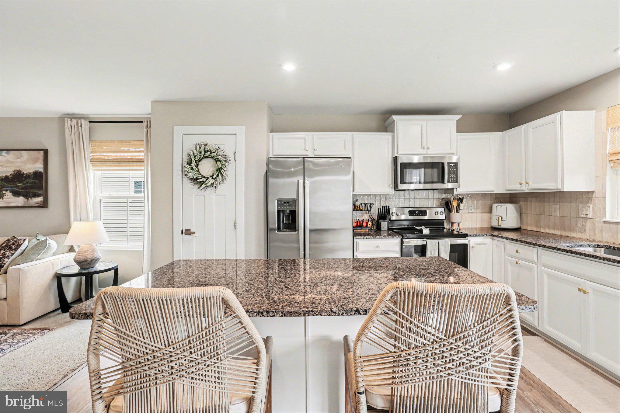 7202 Parchment Circle Ruther Glen, VA 22546 - Photo 7 of 30 a kitchen with stainless steel appliances kitchen island granite countertop a refrigerator a stove a sink a dining table and chairs with wooden floor