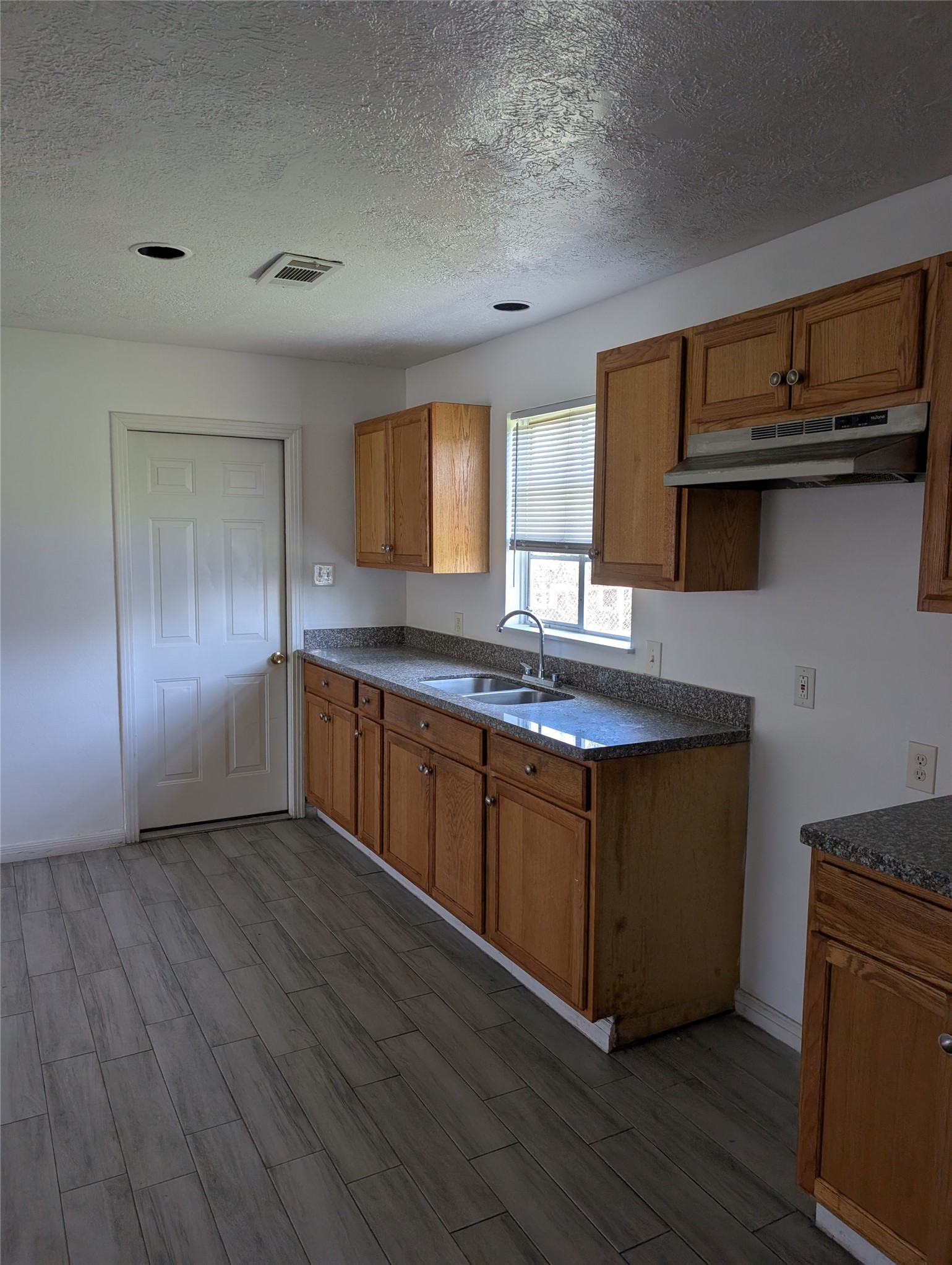 109 East Parker Road Houston, TX 77076 - Photo 3 of 11 a kitchen with stainless steel appliances granite countertop a sink and wooden cabinets
