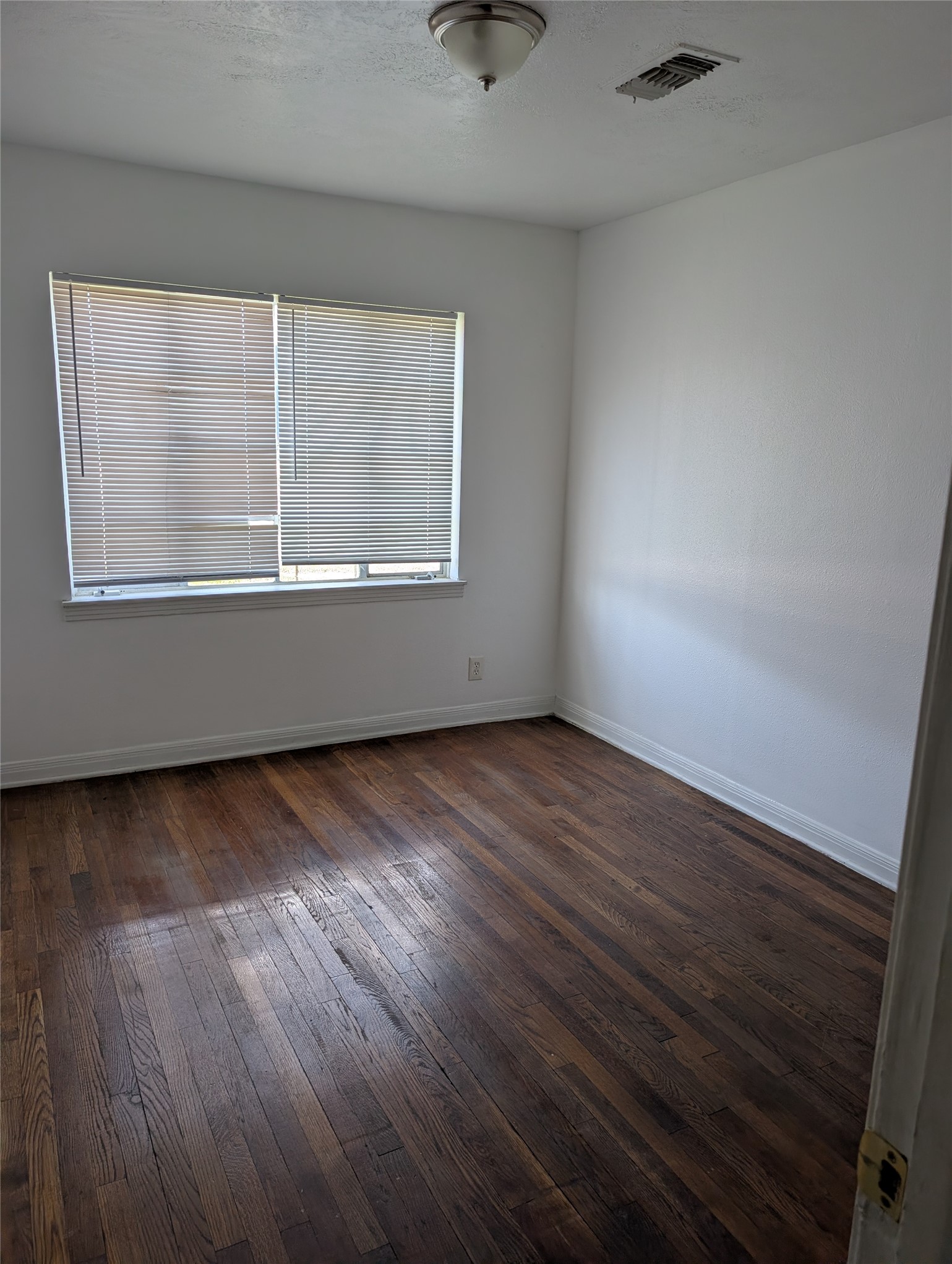 109 East Parker Road Houston, TX 77076 - Photo 5 of 11 an empty room with wooden floor and windows