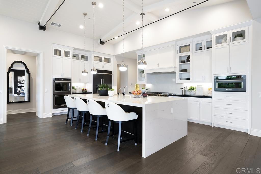 15527 Artesian Ridge San Diego, CA 92127 - Photo 4 of 32 a kitchen with stainless steel appliances granite countertop a stove a refrigerator a kitchen island with white cabinets and wooden floor