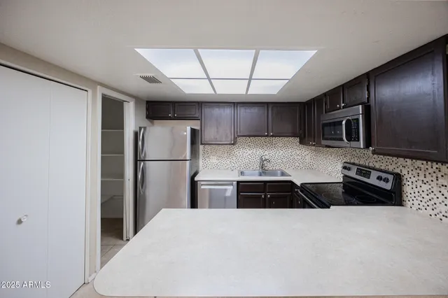 a kitchen with granite countertop a refrigerator and a stove top oven