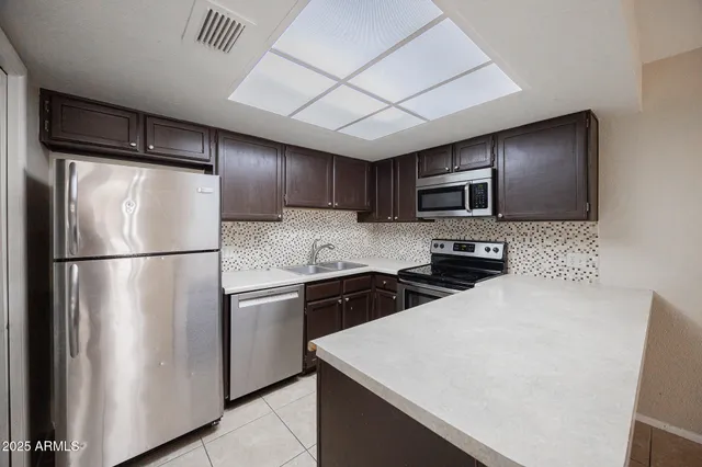 a kitchen with stainless steel appliances granite countertop a refrigerator a stove a sink dishwasher and a refrigerator with wooden floor