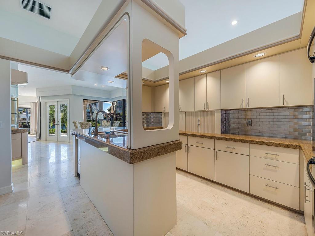 4217 Crayton Road Naples, FL 34103 - Photo 7 of 22 a large white kitchen with kitchen island a large counter top space and stainless steel appliances
