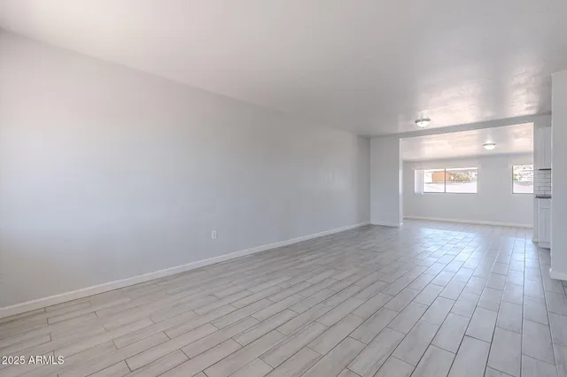 a view of empty room with window and wooden floor