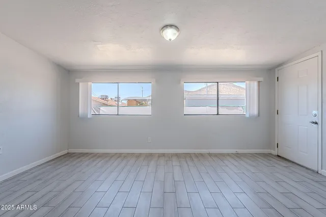 an empty room with wooden floor and windows