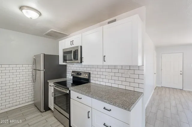 a kitchen with granite countertop a sink stove and refrigerator