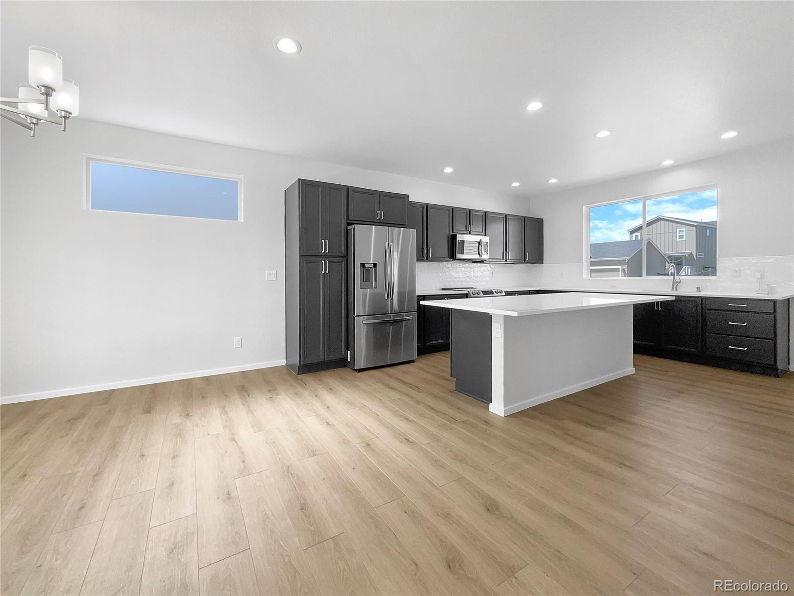 12825 Eagle River Road Firestone, CO 80504 - Photo 18 of 32 a open kitchen with stainless steel appliances granite countertop a stove top oven a sink dishwasher a refrigerator and a dining table with wooden floor