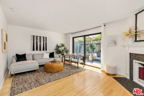 a living room with furniture a fireplace and potted plants with wooden floor