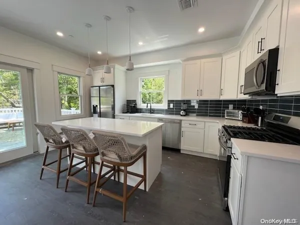 a kitchen with stainless steel appliances granite countertop white cabinets a sink and a stove