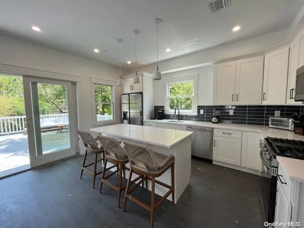 a kitchen with granite countertop a stove a sink a dining table and chairs