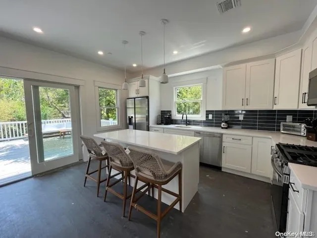 a kitchen with granite countertop a stove a sink a dining table and chairs