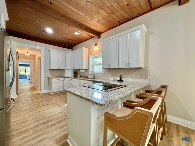 a kitchen with granite countertop a sink stove and cabinets
