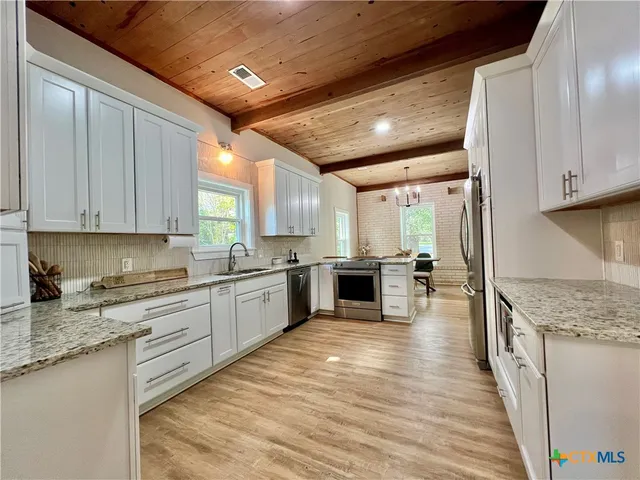 a large kitchen with stainless steel appliances granite countertop a large counter top a stove and a refrigerator