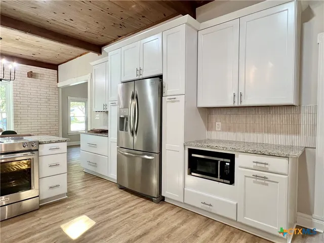 a kitchen with stainless steel appliances white cabinets and a refrigerator