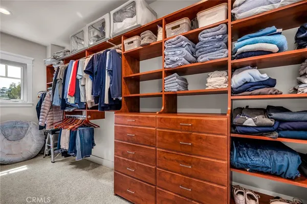 a view of walk in closet with clothes and shoes