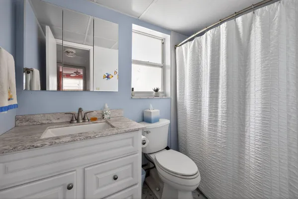 a bathroom with a granite countertop sink toilet and mirror