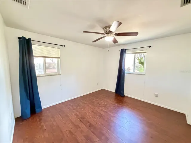 a view of empty room with wooden floor and fan