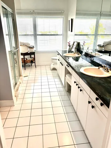 a large white kitchen with granite countertop a stove a sink a counter space and a window