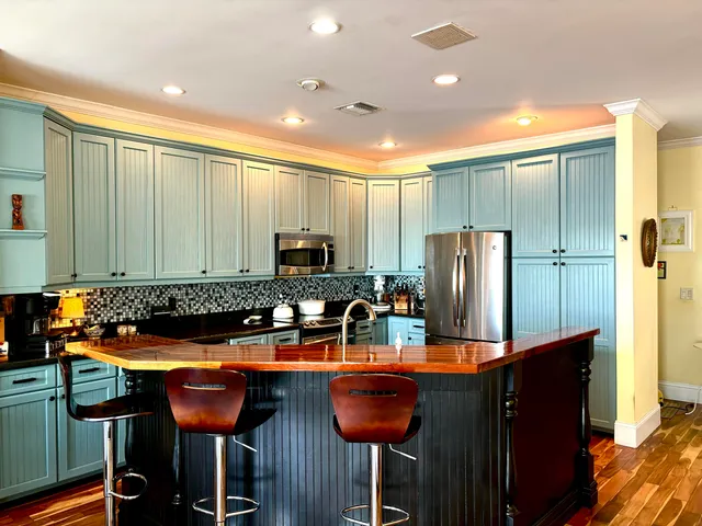 a kitchen with stainless steel appliances granite countertop a table chairs and a refrigerator