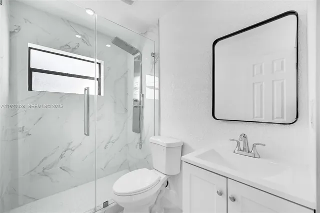a bathroom with a granite countertop sink toilet a mirror and shower