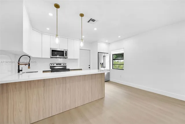 a kitchen with stainless steel appliances a sink a stove a microwave and white cabinets