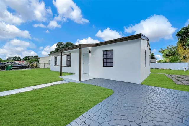 a view of a house with a big yard potted plants and large tree
