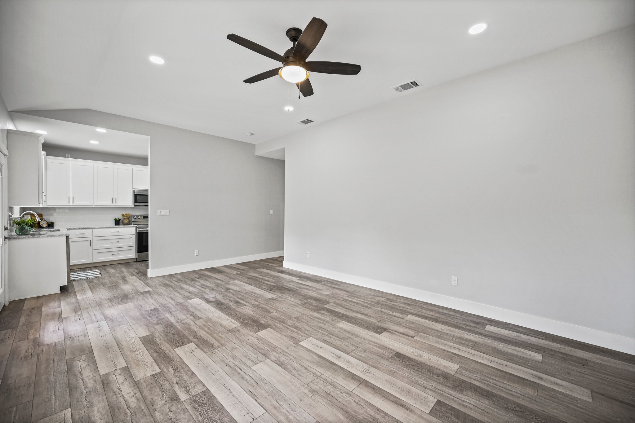 231 North Rainbow Ranch Road Wimberley, TX 78676 - Photo 12 of 40 An open-concept living space with sleek hardwood flooring flows seamlessly into a modern kitchen.
