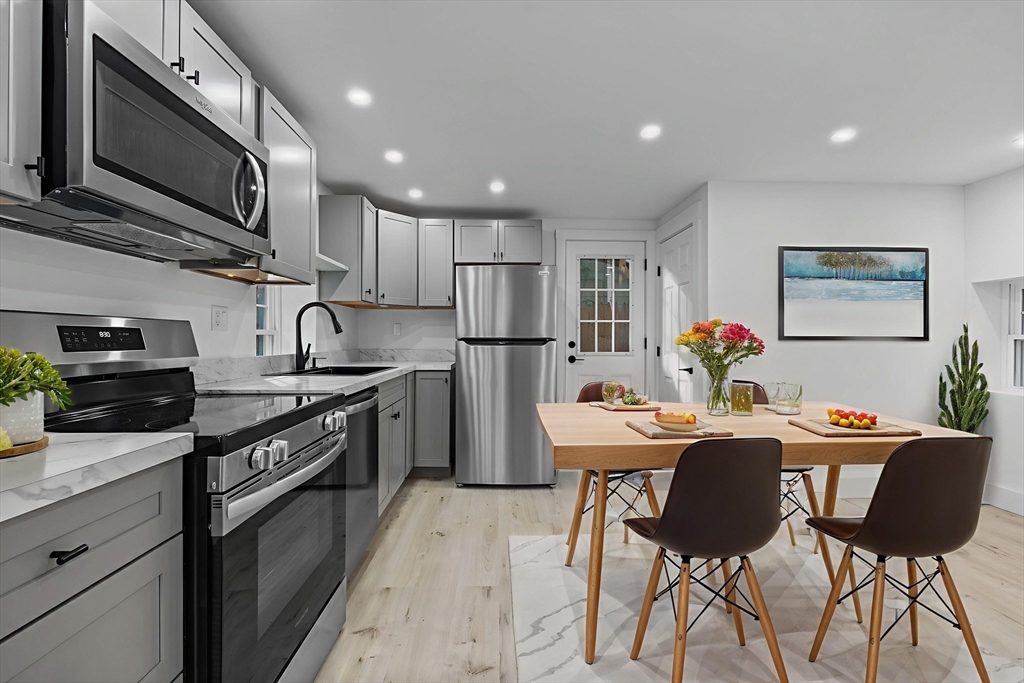 37 Fountain Road, Unit 2 Arlington, MA 02476 - Photo 20 of 25 a kitchen with stainless steel appliances granite countertop a stove refrigerator a microwave oven with a dining table and chairs