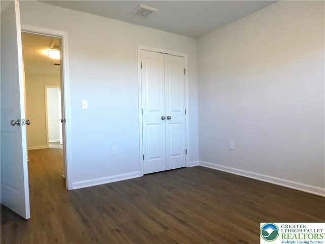 a view of an empty room with wooden floor and a bathroom