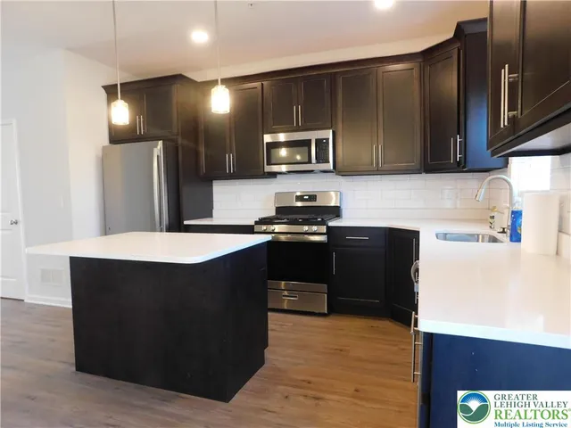 a kitchen with stainless steel appliances a refrigerator a sink a stove a microwave and wooden cabinets