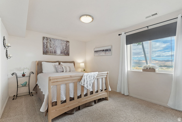 14883 Tooele Lane Draper, UT 84020 - Photo 36 of 49 Carpeted bedroom with a large window featuring roller shades and white curtains, offering a distant mountain landscape