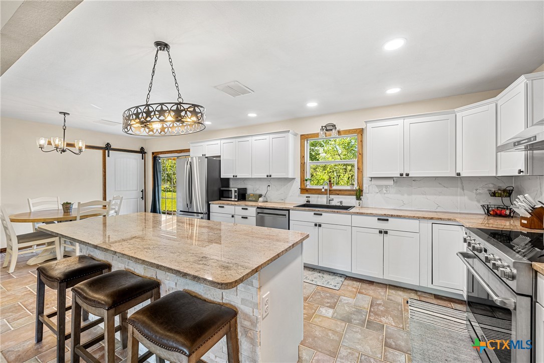 370 County Road 3106 Kempner, TX 76539 - Photo 13 of 34 a kitchen with stainless steel appliances granite countertop a stove top oven a sink dishwasher a dining table and chairs with wooden floor