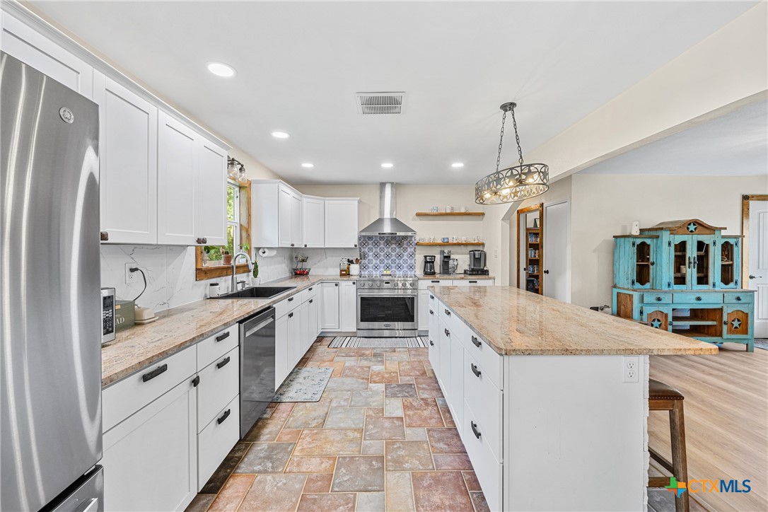 370 County Road 3106 Kempner, TX 76539 - Photo 15 of 34 a large kitchen with kitchen island a stove a sink a refrigerator and a wooden floor