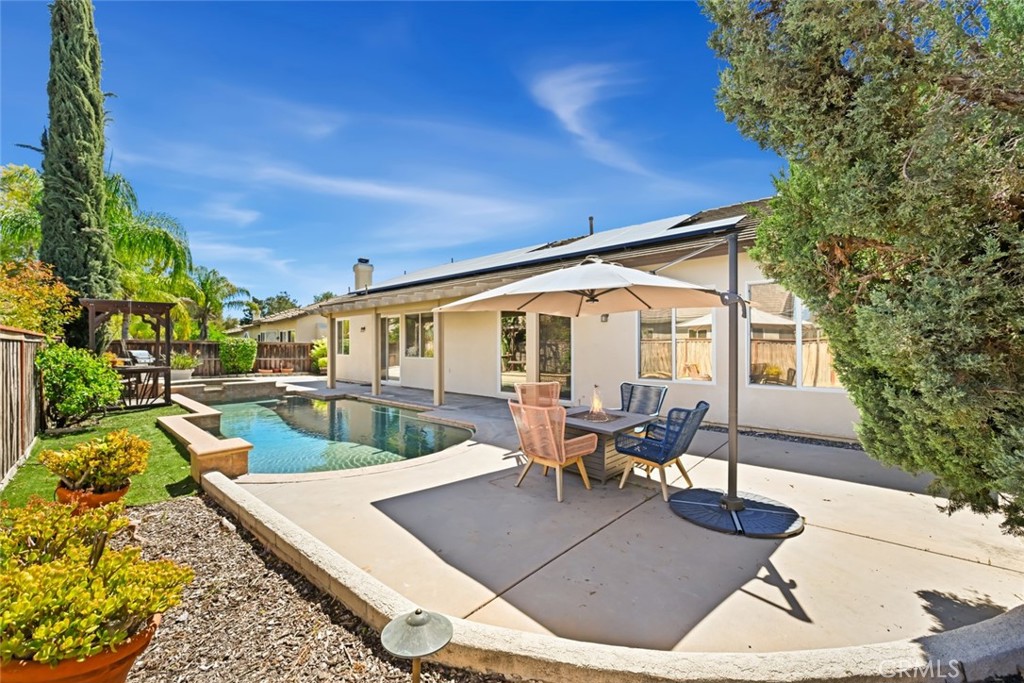 26764 Kingwood Road Murrieta, CA 92563 - Photo 34 of 42 a view of a patio with couches table and chairs under an umbrella with large trees